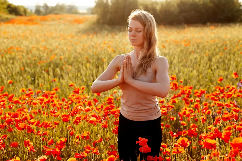 A woman meditating in the open flower field.