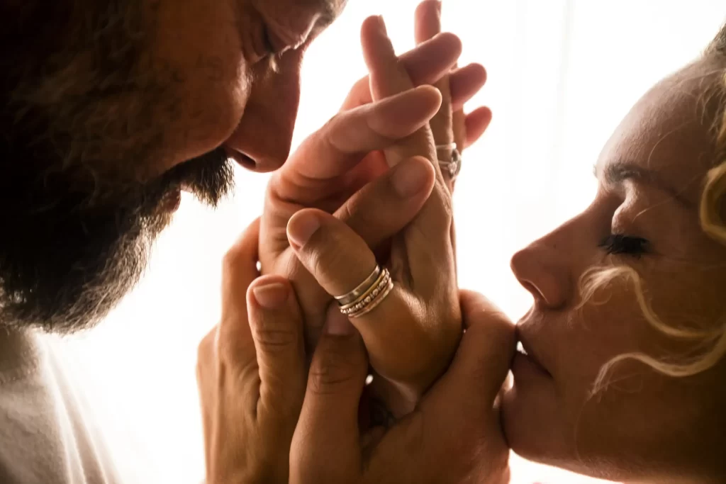 A zoomed image of a couple holding hands while eyes closed.