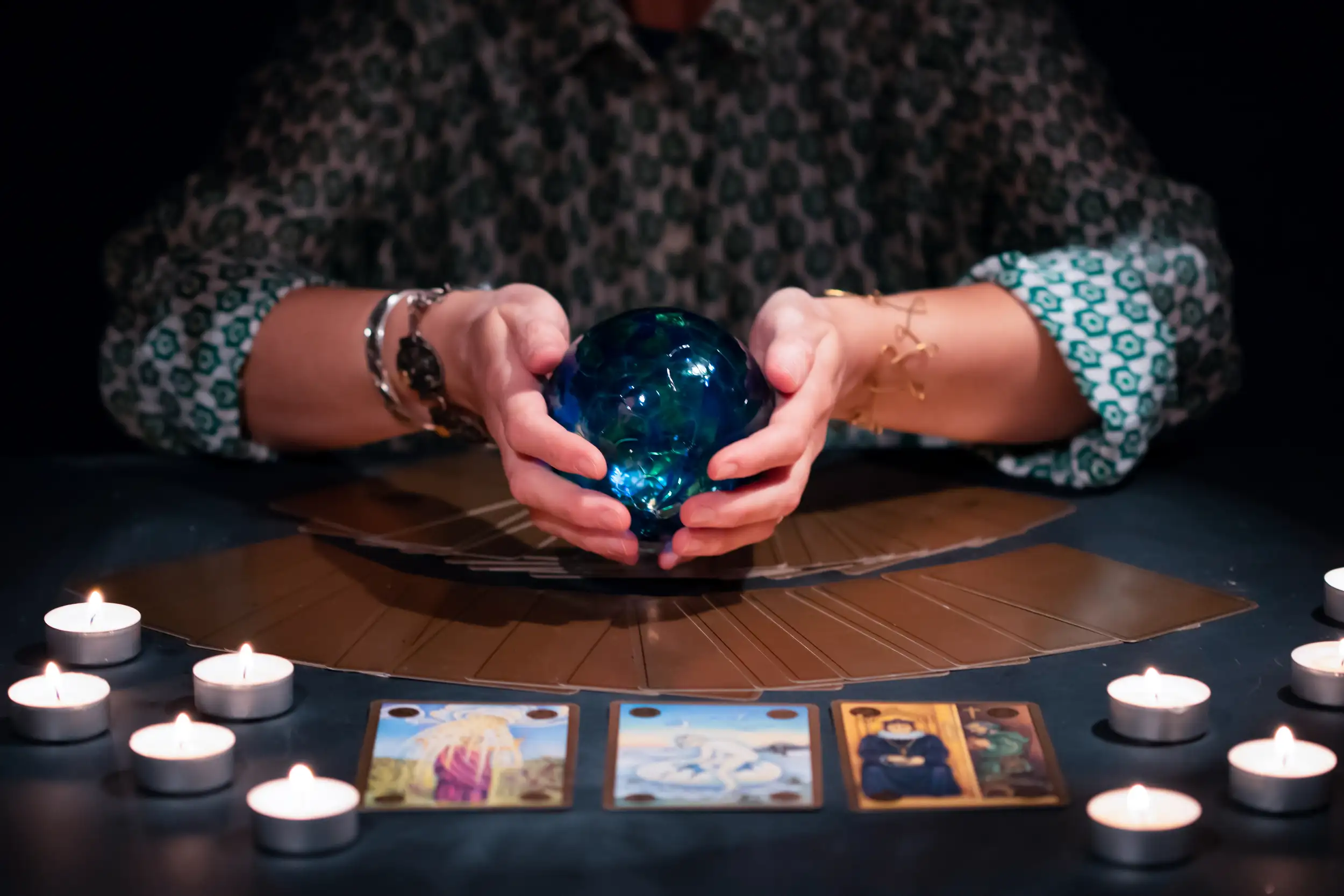 A fortune tellers table with tarot cards and crystal ball.