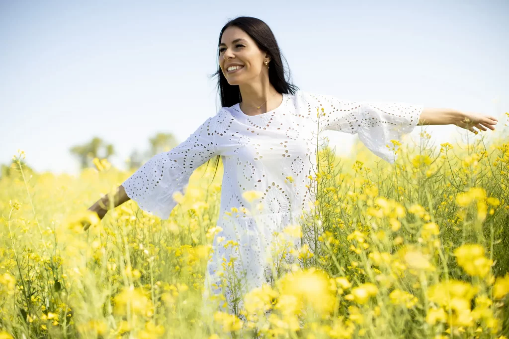 A woman in white dress happy in the rapeseed fields.